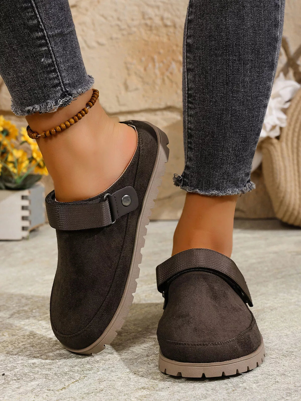 Brown clogs worn with jeans on a neutral background