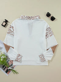 White blouse with leopard print sleeves on a beige background