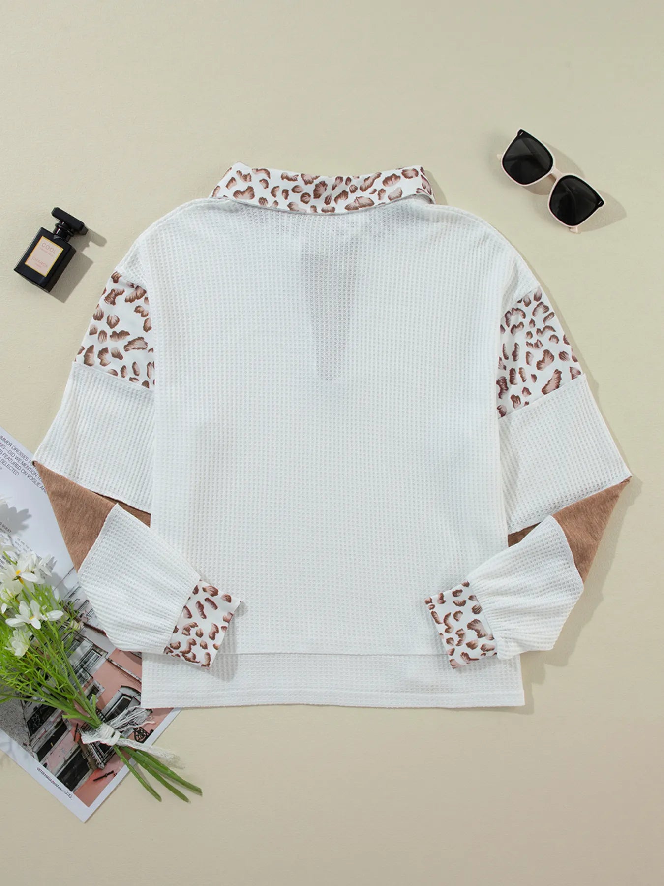 White blouse with leopard print sleeves on a beige background