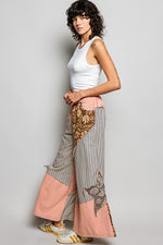 Woman wearing a white sleeveless top and patterned pants on a gray background