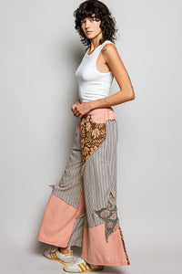 Woman wearing a white sleeveless top and patterned pants on a gray background