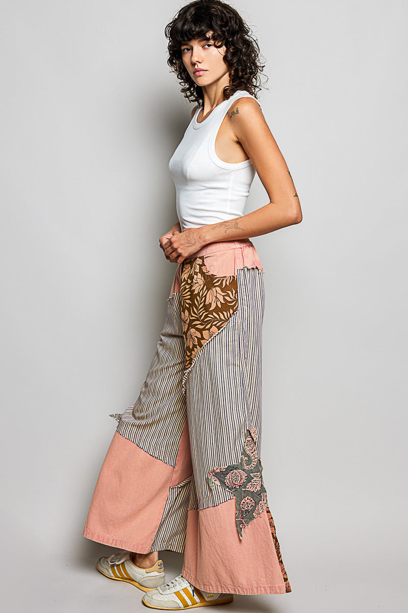 Woman wearing a white sleeveless top and patterned pants on a gray background