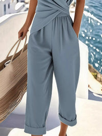 Person wearing a light blue jumpsuit by a waterfront.