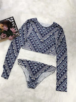 Navy and white patterned long-sleeve top and bikini bottom on a white surface with a magazine.