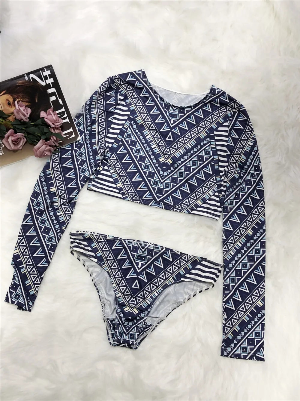 Navy and white patterned long-sleeve top and bikini bottom on a white surface with a magazine.
