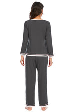Woman wearing a gray pajama set with white trim on a white background