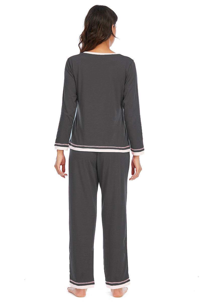 Woman wearing a gray pajama set with white trim on a white background