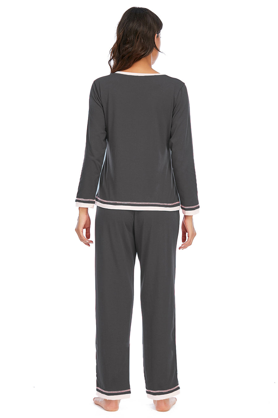 Woman wearing a gray pajama set with white trim on a white background