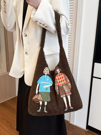 Brown tote bag with embroidered figures held by a person wearing a white coat.