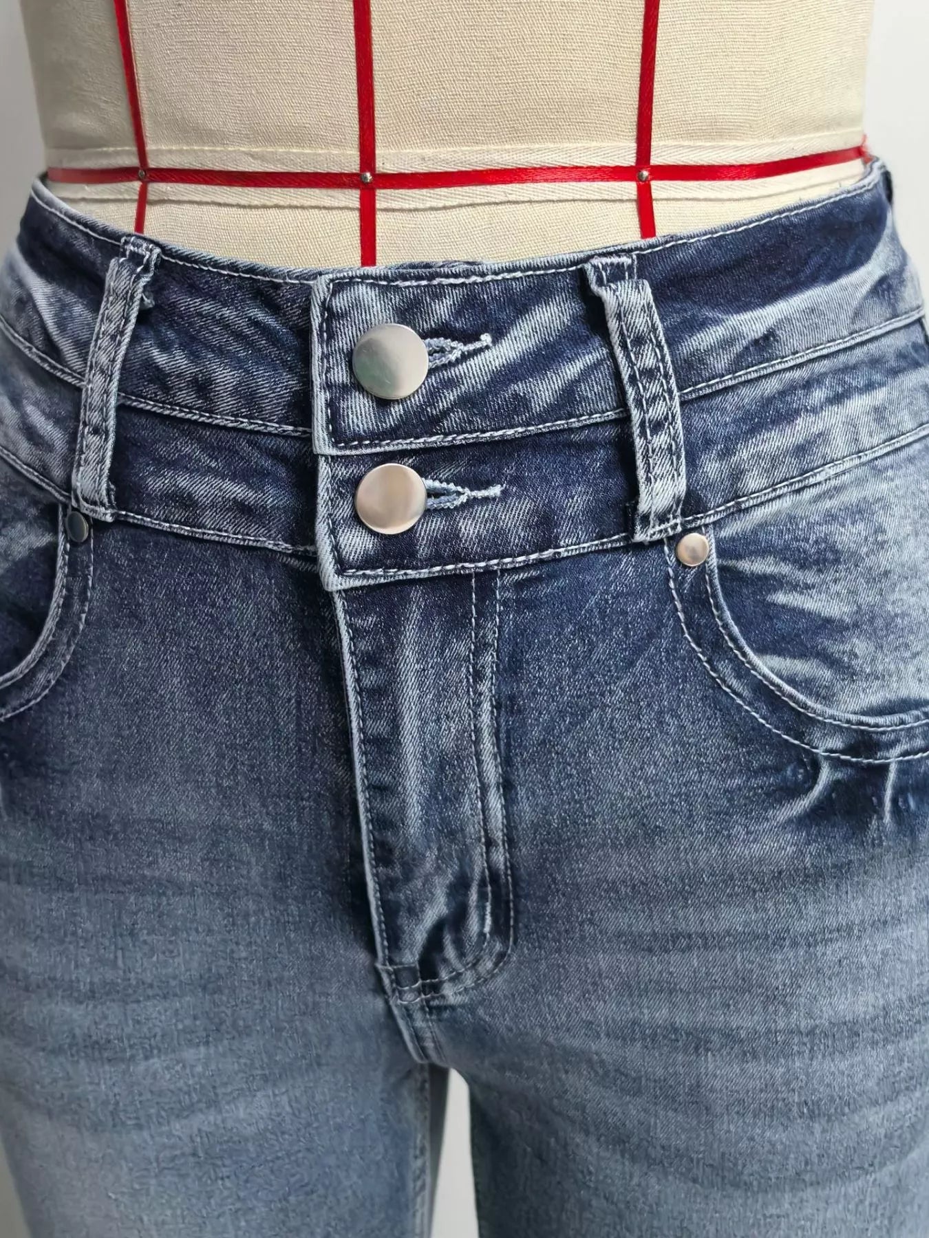 Close-up of blue jeans with a checkered shirt in the background