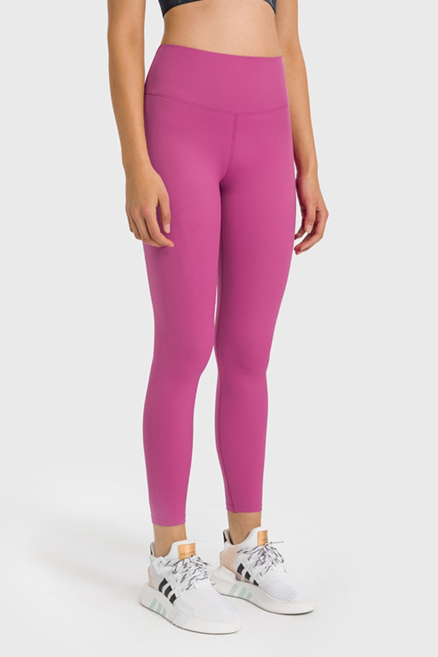 Person wearing pink leggings and white sneakers on a white background
