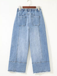 Light blue denim wide-leg pants on a hanger against a white background