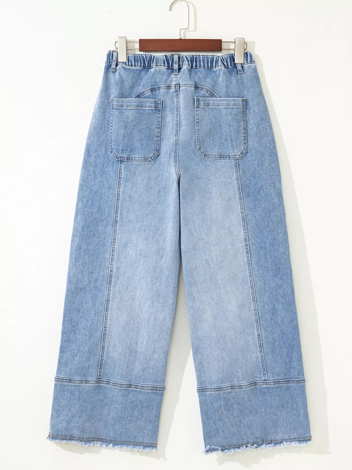 Light blue denim wide-leg pants on a hanger against a white background