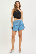 Woman wearing a black top and blue denim shorts on a white background