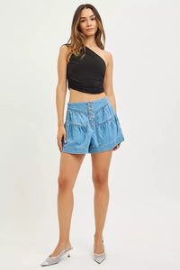 Woman wearing a black top and blue denim shorts on a white background