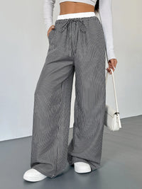 Person wearing black and white striped wide-leg pants with a plain background