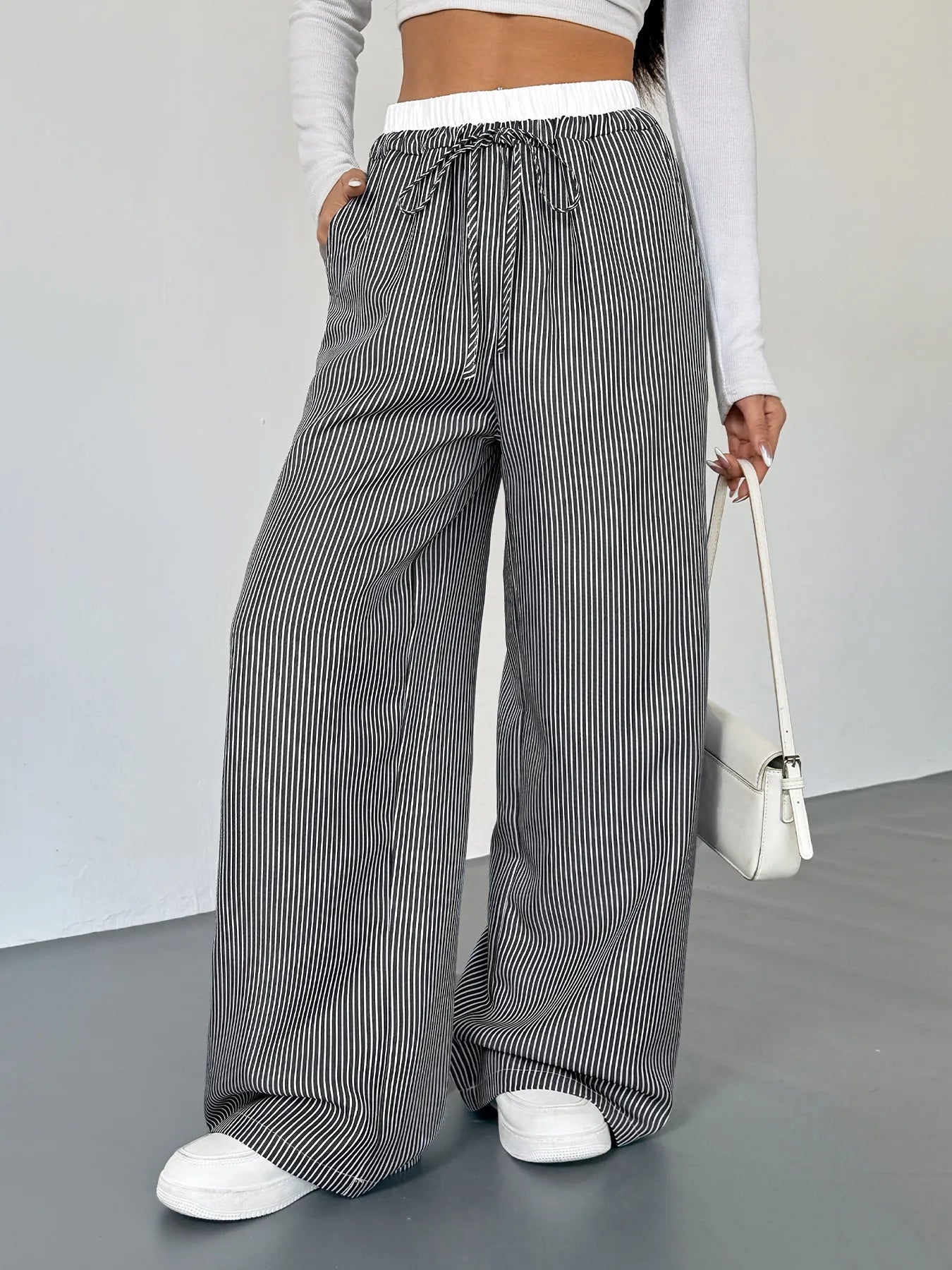 Person wearing black and white striped wide-leg pants with a plain background