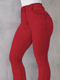 Red pants worn by a person against a gray concrete wall.