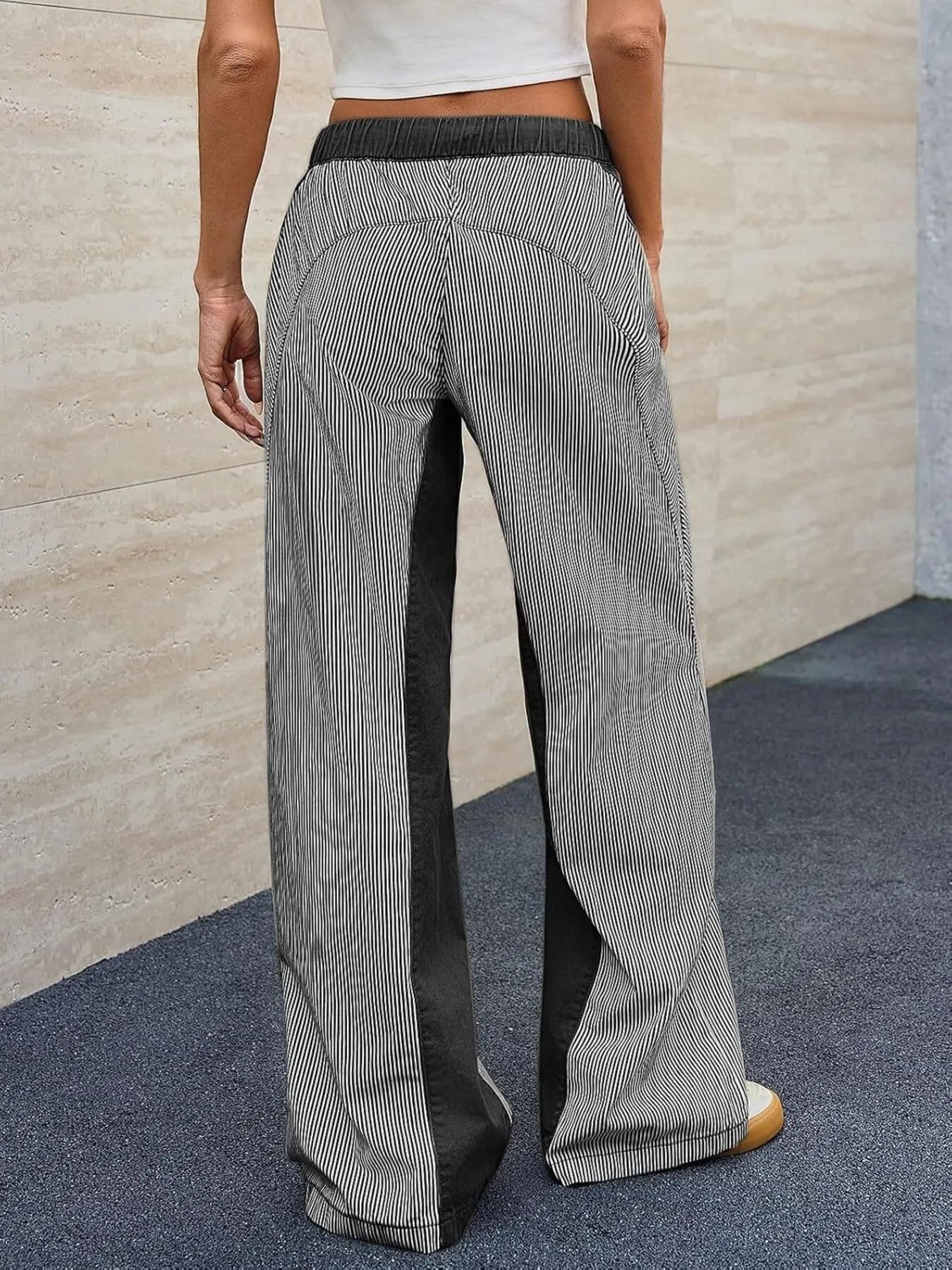 Person wearing gray wide-leg pants with a white background