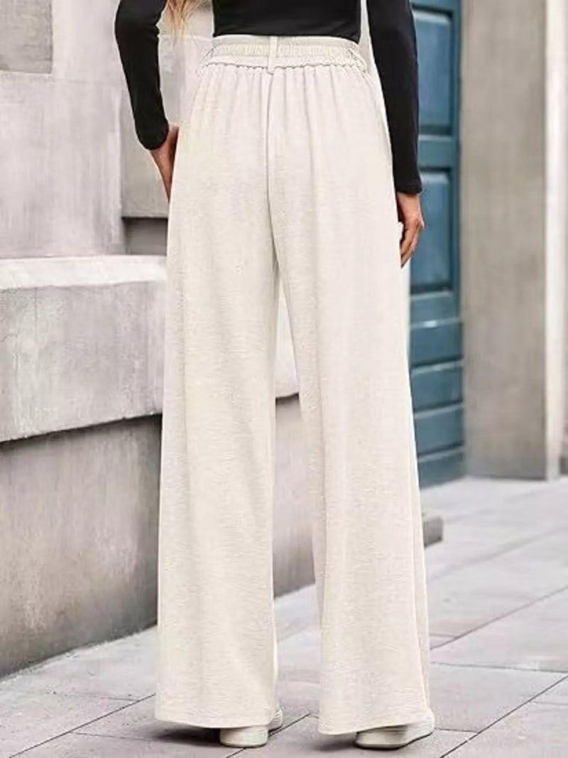 Person wearing beige wide-leg pants standing on a stone staircase.