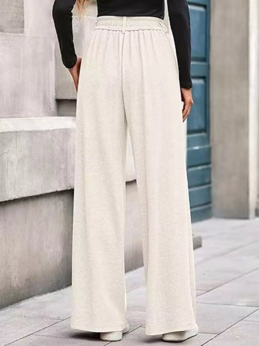 Person wearing beige wide-leg pants standing on a stone staircase.