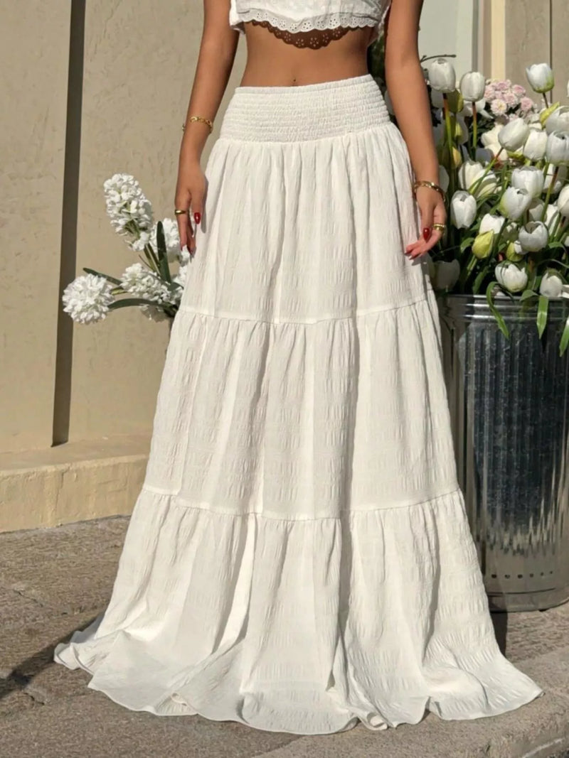 Person wearing a white tiered skirt with floral arrangements in the background
