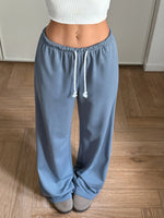 Blue sweatpants with a white top on a wooden floor