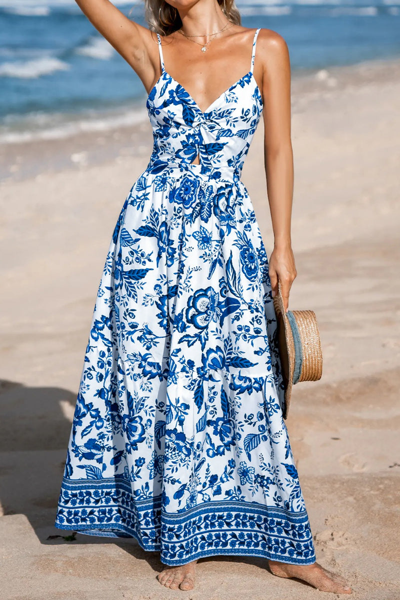 Woman in a blue and white floral dress standing on a beach.