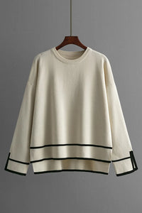 Beige sweater with black trim on a wooden hanger against a gray background