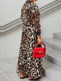 Person wearing a leopard print dress holding a red handbag on a staircase.