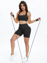 Woman in black athletic wear holding resistance bands on a white background