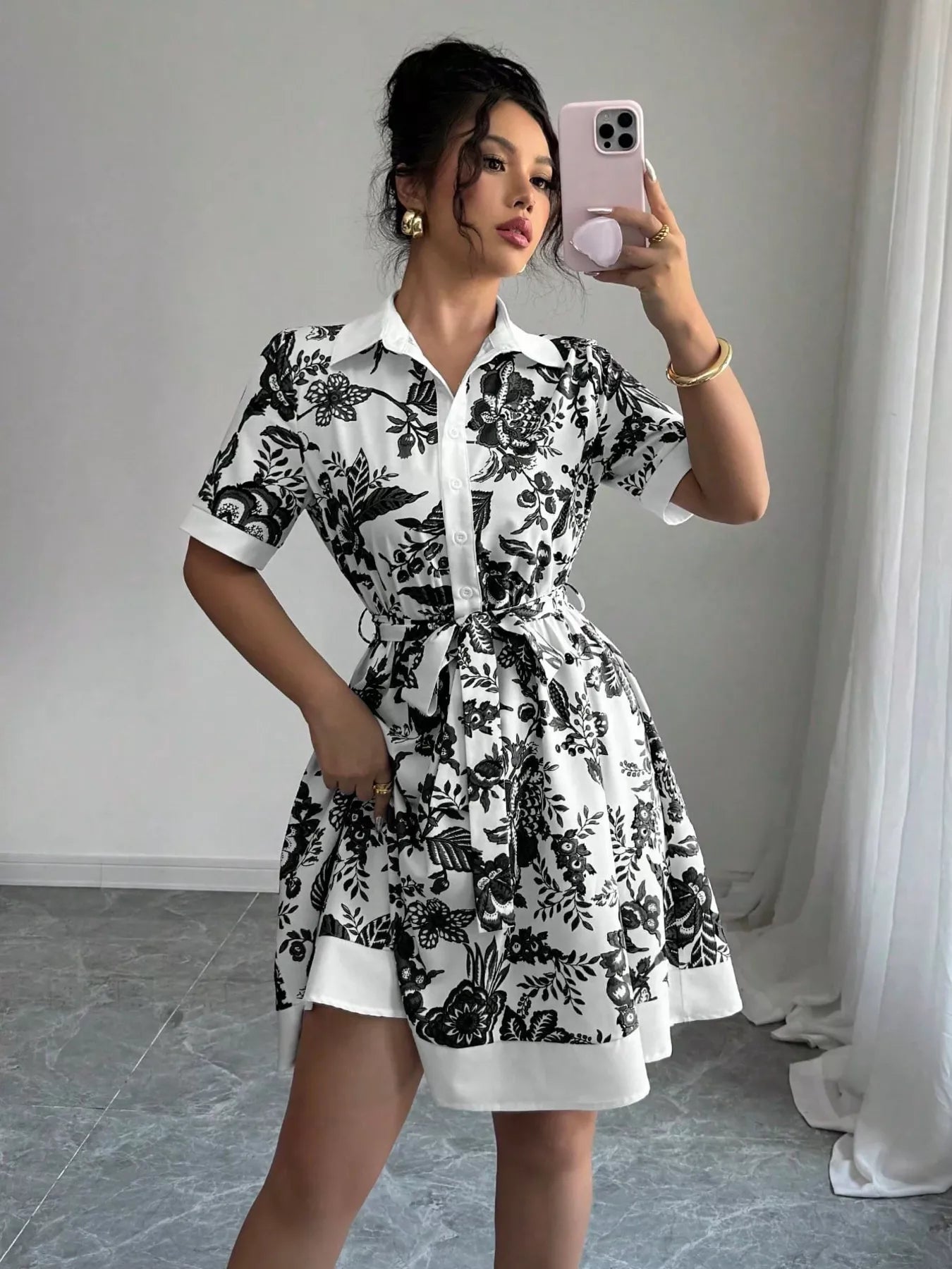 Woman taking a mirror selfie wearing a black and white floral dress.