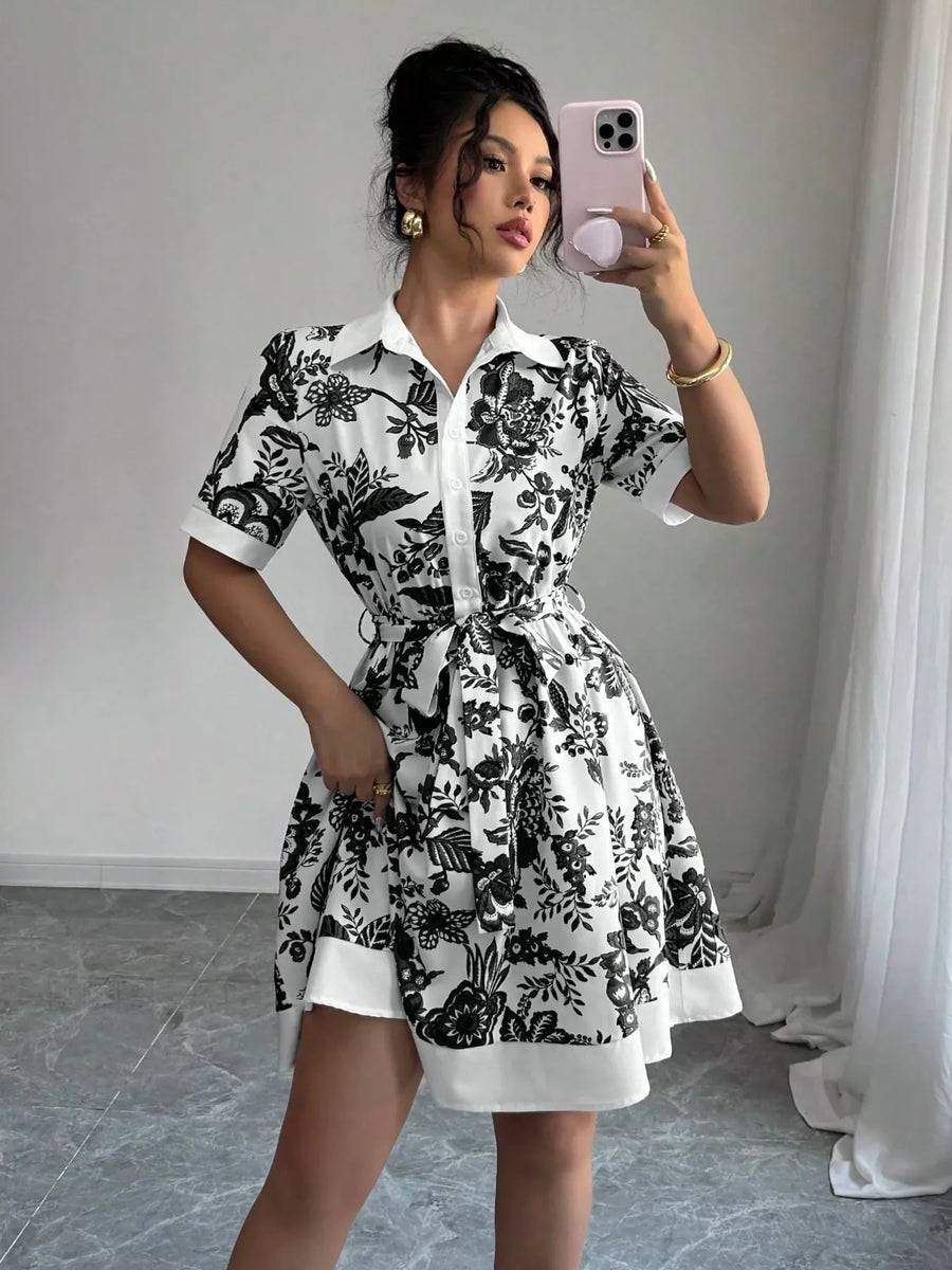 Woman taking a mirror selfie wearing a black and white floral dress.