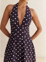 Navy blue dress with white polka dots worn by a model against a neutral background