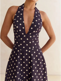 Navy blue dress with white polka dots worn by a model against a neutral background