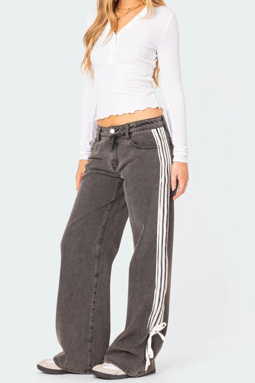 Person wearing gray jeans with white stripes on a plain background