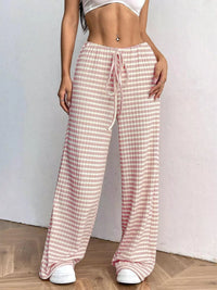 Person wearing pink and white checkered pants on a plain background