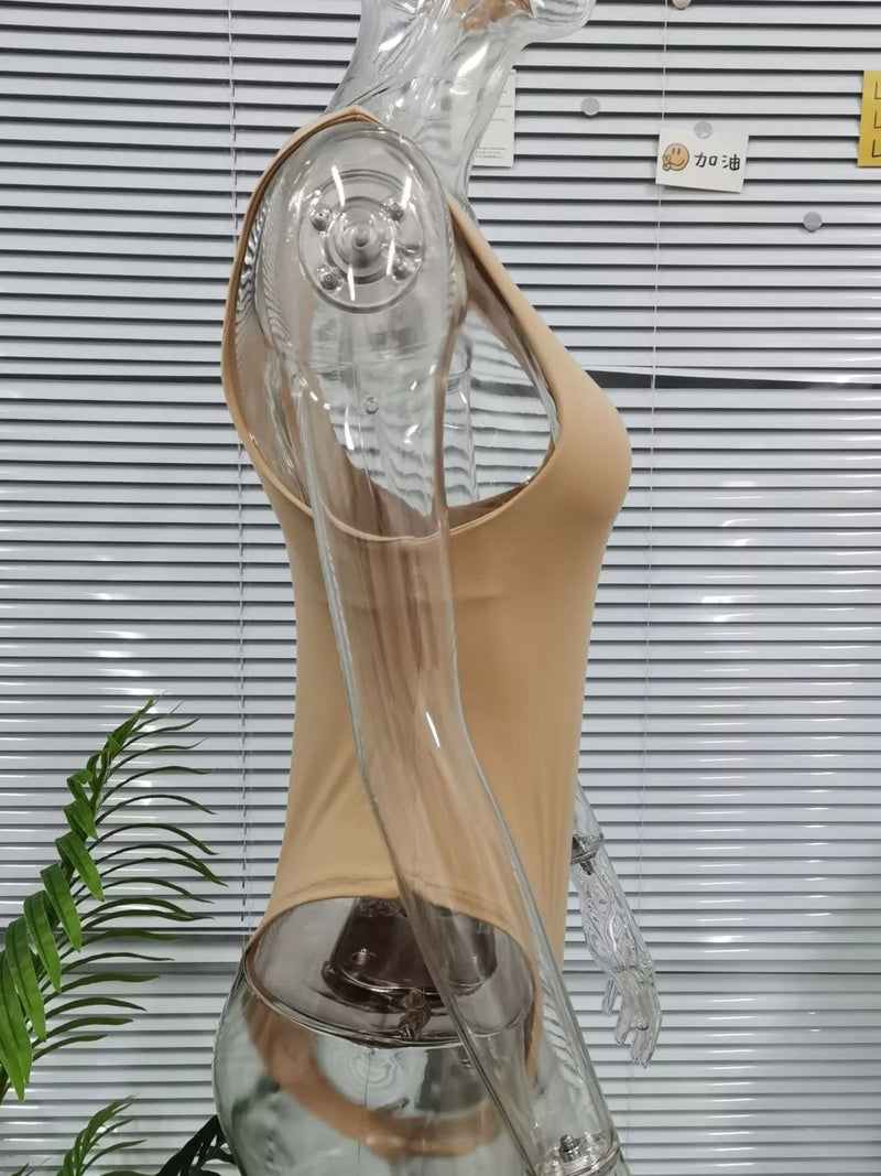 Beige high-heeled shoe on a mannequin with clear heel against a striped wall.