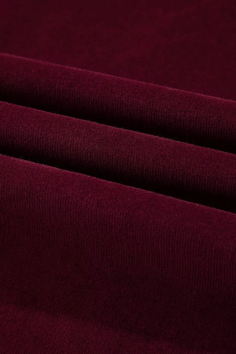 A close-up of draped burgundy knit fabric with soft folds showing its fine ribbed texture.