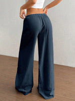Person wearing blue wide-leg pants on a wooden floor with a neutral background