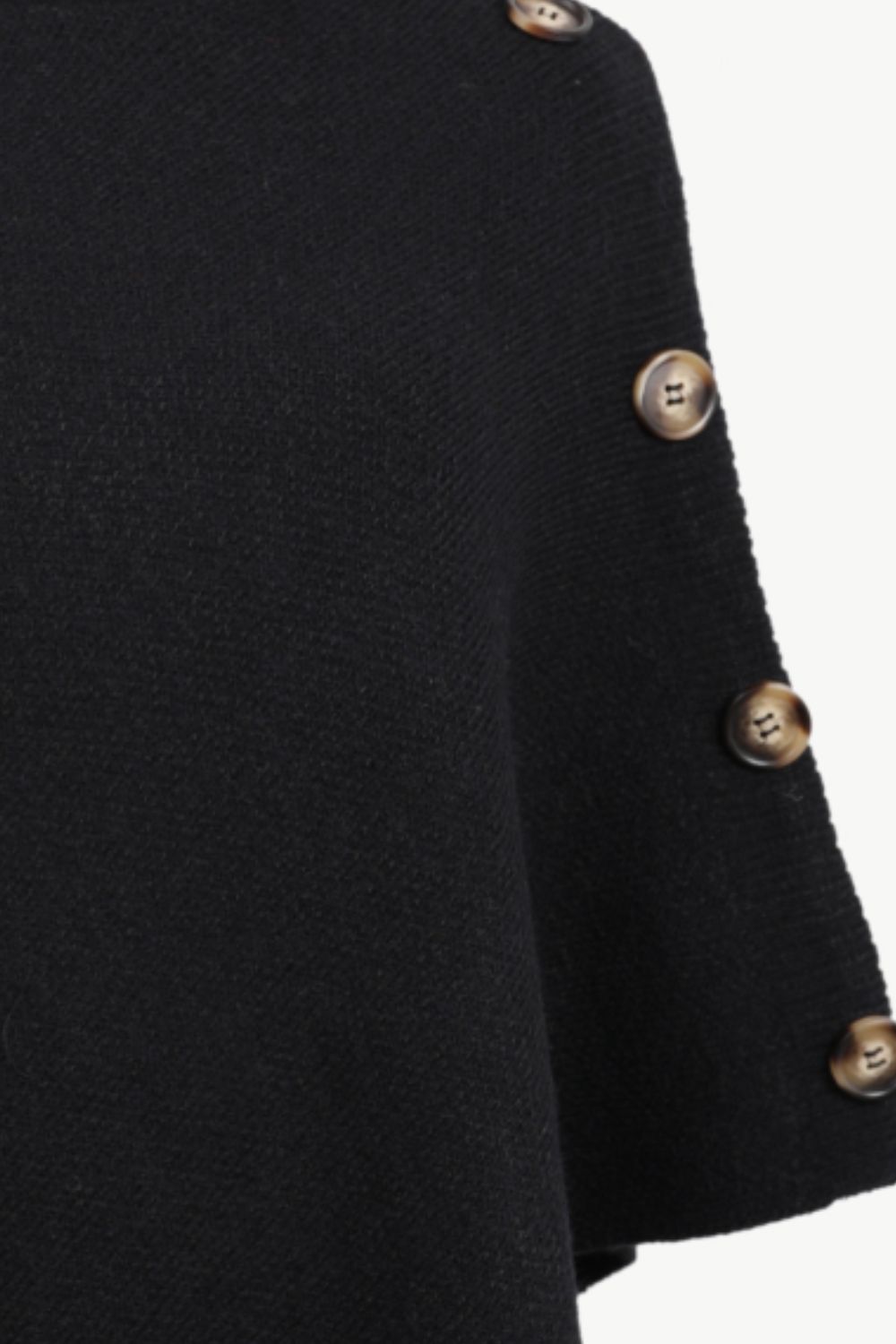 Close-up of a black knit garment sleeve with decorative metallic buttons along the edge, shown against a plain light background.