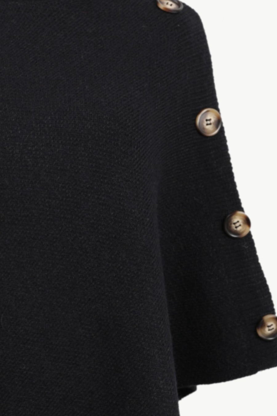 Close-up of a black knit garment sleeve with decorative metallic buttons along the edge, shown against a plain light background.