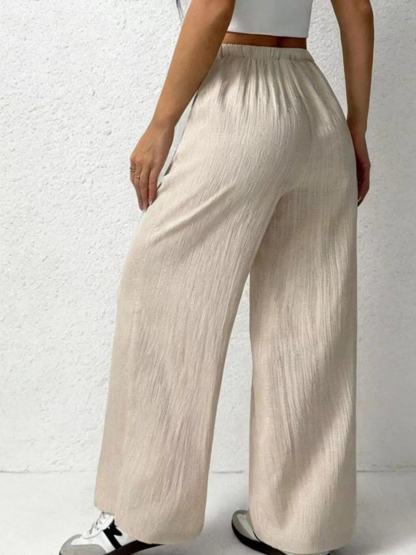 Beige wide-leg pants worn by a person on a white background