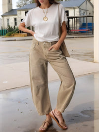 Person wearing a white t-shirt, beige pants, and sandals on a street.