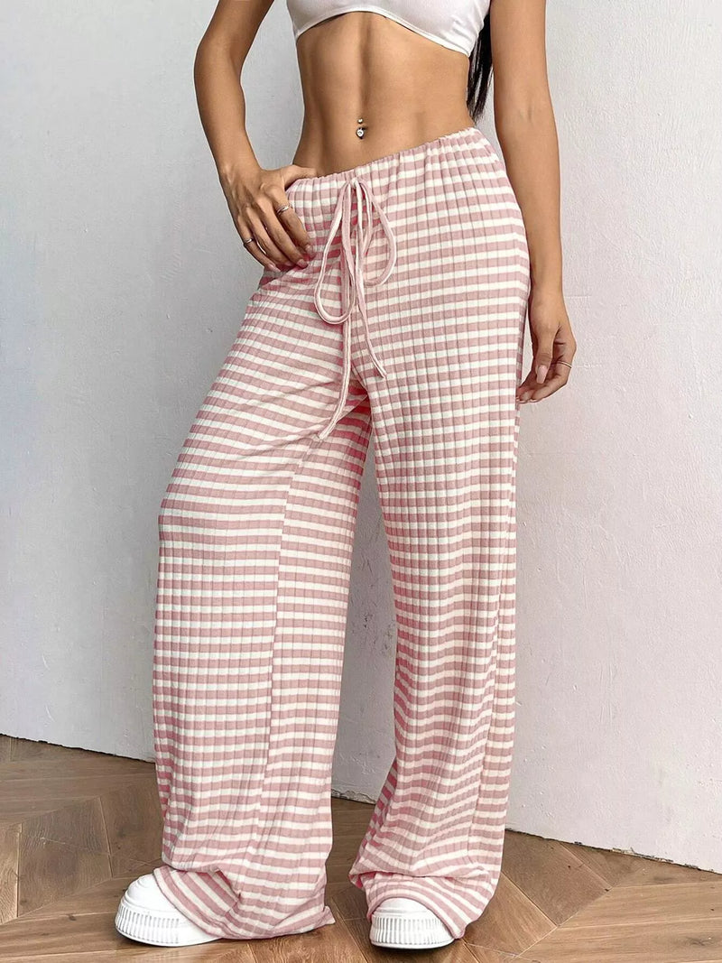 Person wearing pink and white checkered pants with a plain background