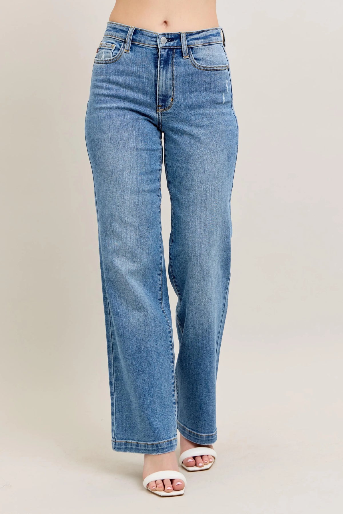 Blue jeans worn by a person on a beige background
