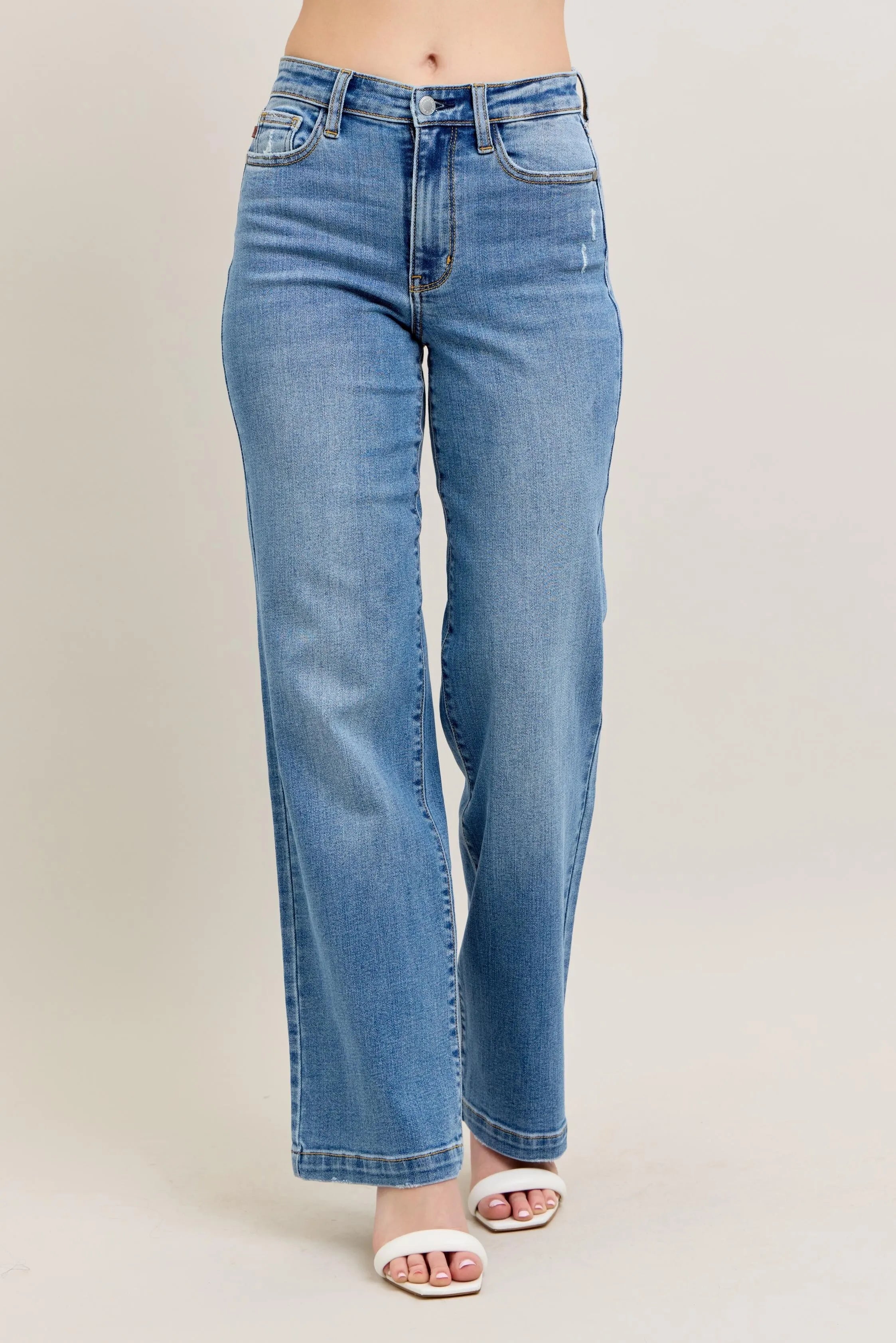 Blue jeans worn by a person on a beige background