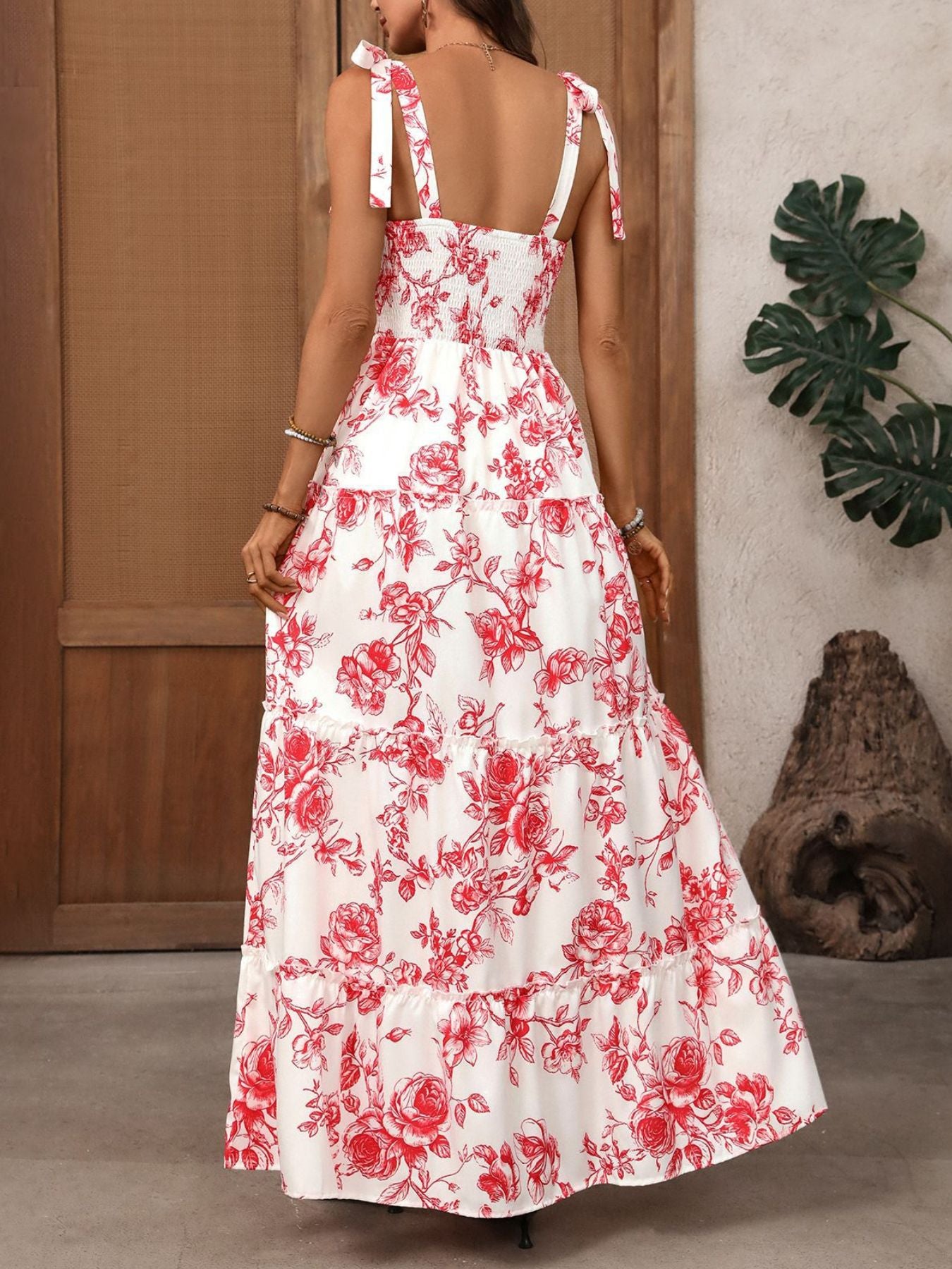 Woman wearing a white dress with red floral pattern indoors.