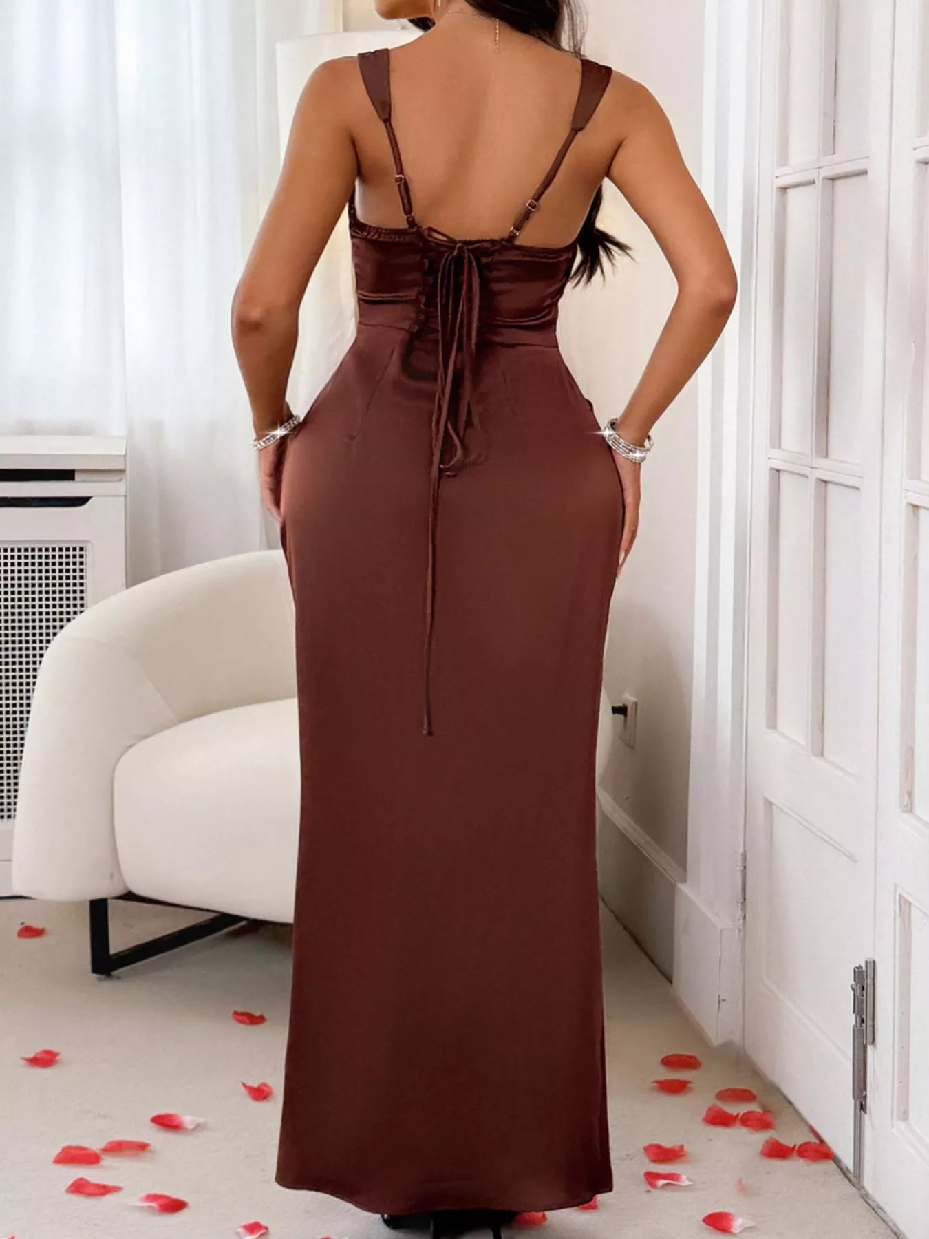 Woman wearing a brown dress with a backless design in a room with white walls and a white chair.