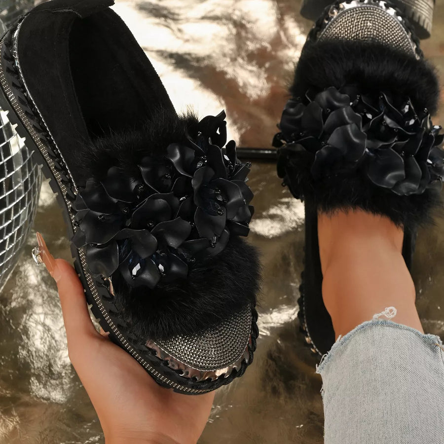 Black floral sandals with rhinestone details worn by a person.